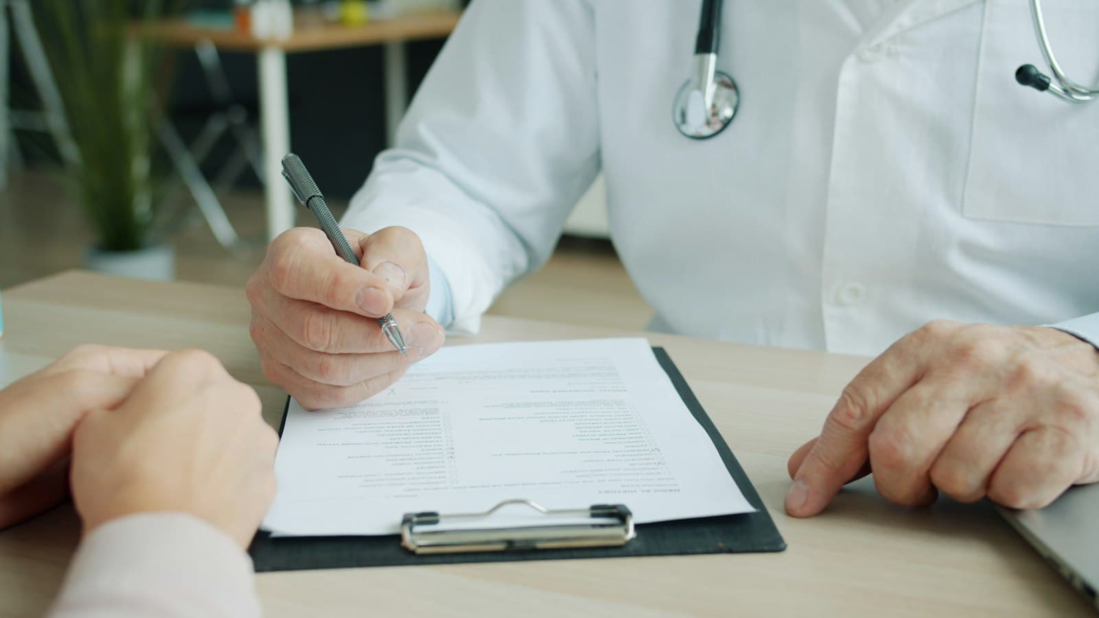 Médico escribiendo en el expediente de un paciente